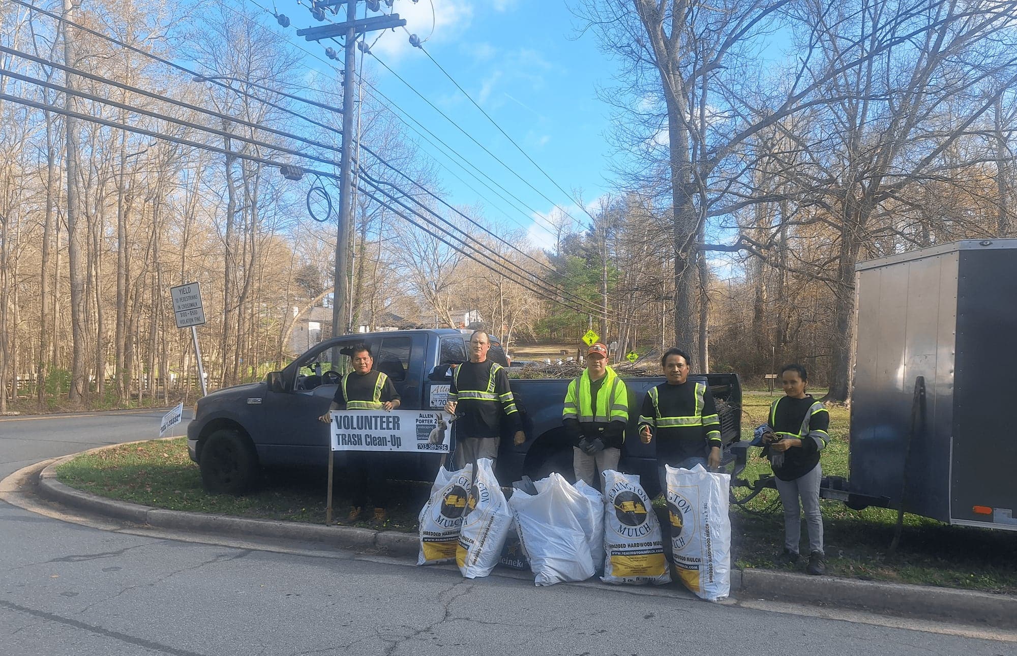 The Allen Porter 2 crew in safety vests beside a pickup truck and filled trash bags at one of their volunteer clean-ups